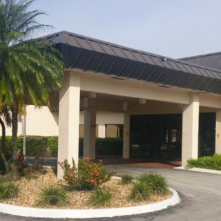 A building entrance with a covered driveway and landscaped area featuring a palm tree.
