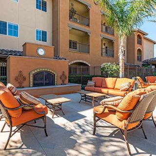 An outdoor patio area with comfortable seating and a fireplace in front of an apartment building.