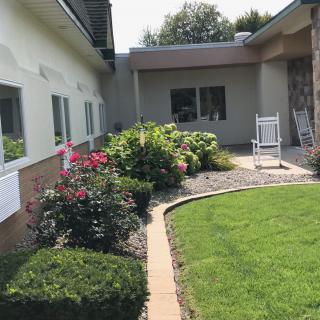 A beautifully landscaped garden with a variety of flowers and bushes, alongside a walkway leading to a building's exterior.