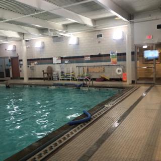 An indoor swimming pool area with clear water and recreational equipment.