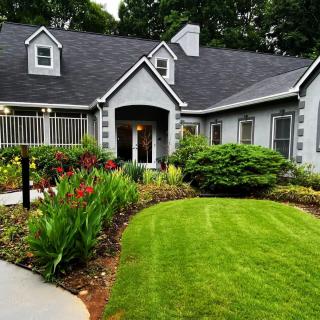 A beautiful suburban house with a well-maintained garden and lush green lawn.