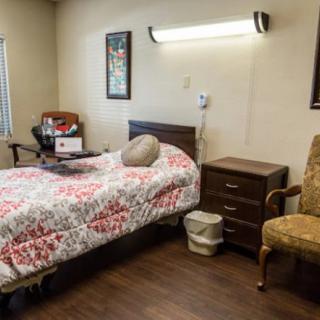 A cozy room in a healthcare facility with a bed, nightstand, and chair.