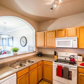 A modern kitchen with wooden cabinets, a sink, and appliances including an oven and microwave.