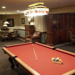 A cozy game room featuring a red felt pool table and ambient lighting.
