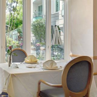 An elegantly set table by a large window offering a garden view in a restaurant.