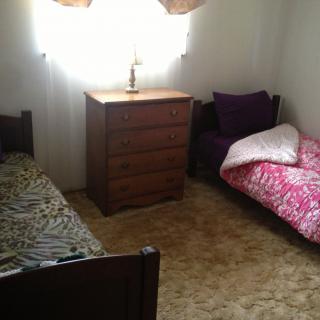 A simple bedroom with two twin beds and a dresser.