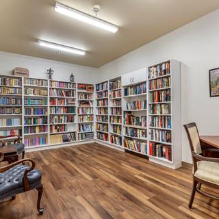 A cozy library room with bookshelves lining the walls and comfortable seating.