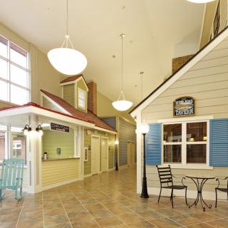 A spacious indoor hallway designed to resemble a village street with storefronts and bright lighting.