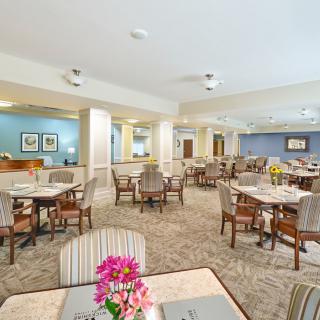 A spacious dining area with well-arranged tables and chairs, decorated with vibrant flowers.