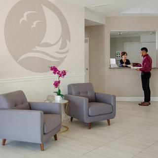 A modern lobby with comfortable seating and a reception desk where two people are conversing.