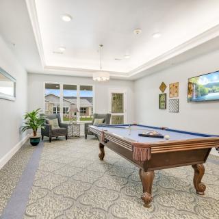 A well-lit game room featuring a billiard table, comfortable seating, and stylish decor.