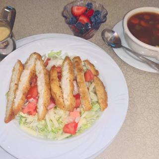 A meal featuring a chicken salad, a bowl of soup, and a cup of mixed berries.