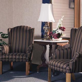 A cozy living room setup featuring two striped chairs, a side table with a lamp, and floral decorations.
