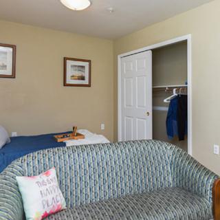 A cozy bedroom with a bed, sofa, and an open closet.
