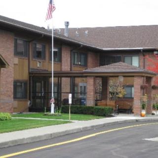 A brick residential building with an entrance featuring an American flag and landscaped surroundings.