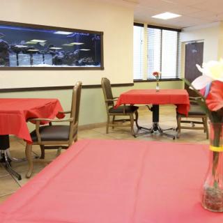 A cozy dining area with tables covered in red tablecloths and simple decorations.