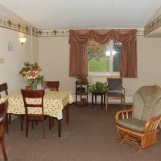 A cozy living and dining area featuring a table with chairs, an armchair, and decorated with curtains.
