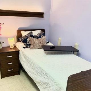 A cozy bedroom with a single bed, nightstand, and decorative pillows.