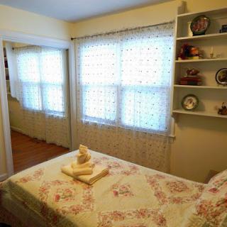 A cozy and inviting bedroom featuring natural light, decorative shelves, and a neatly made bed.