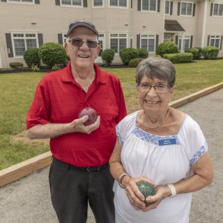 An elderly couple enjoying a game of bocce ball outdoors.