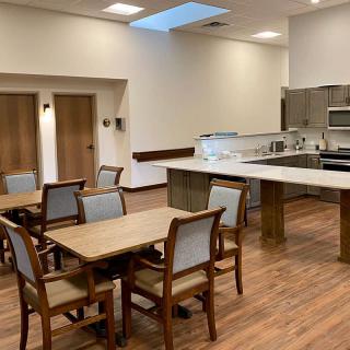 A modern kitchen and dining area with wooden tables and chairs on a wood floor.