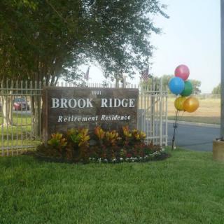 Entrance sign for Brook Ridge Retirement Residence accompanied by colorful balloons.