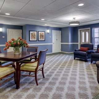 A cozy living room with blue walls, featuring a table with chairs and comfortable seating.