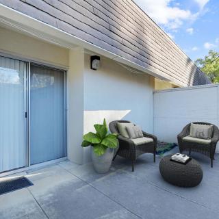 A modern patio with cozy outdoor seating and a potted plant.