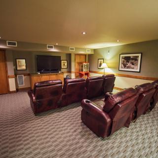 A cozy home theater room with plush seating and a large screen television.