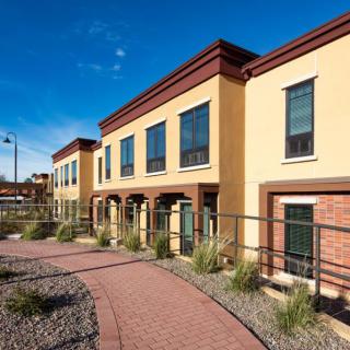 A row of modern townhouses with a well-maintained walkway and landscaped surroundings.