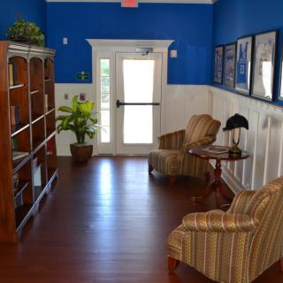 Cozy reading nook with bookshelves, armchairs, and decor in a brightly lit room.