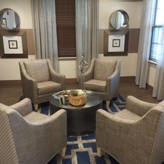 A cozy sitting area with four upholstered chairs around a round table, featuring modern decor and neutral tones.