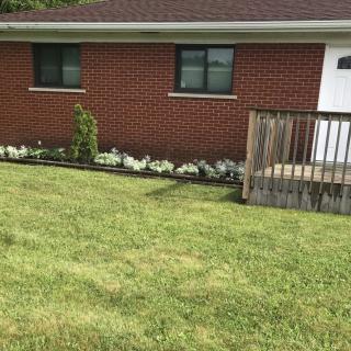 A suburban brick house with a small porch and a well-maintained lawn.