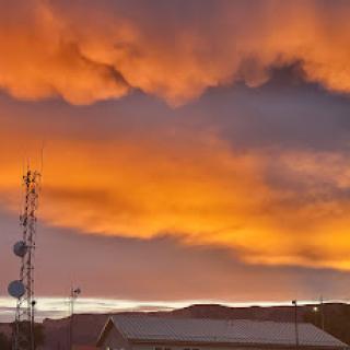 A stunning sunset casts vibrant orange hues across the clouds, silhouetting the landscape.