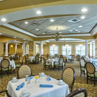 An elegant dining room with neatly arranged tables and chairs, featuring warm lighting and a formal atmosphere.