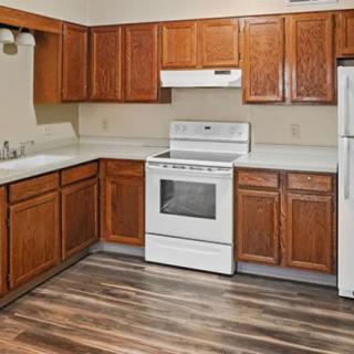 A modern kitchen featuring wood cabinets and white appliances, including a stove and refrigerator.
