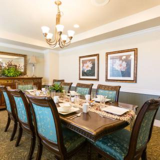 An elegantly furnished dining room with a large table and chairs, complete with decorative elements and a chandelier.