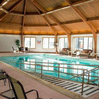 An inviting indoor swimming pool with a wooden domed ceiling and seating area.