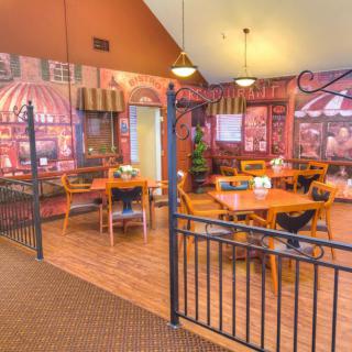A cozy restaurant interior with dining tables and chairs, decorated with artistic wall murals.