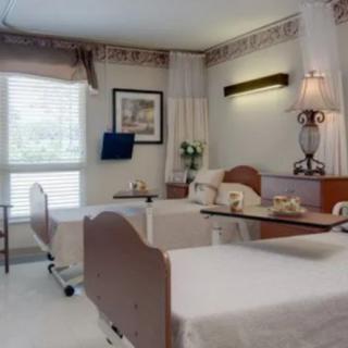 A clean and organized hospital room with two patient beds and bedside tables.