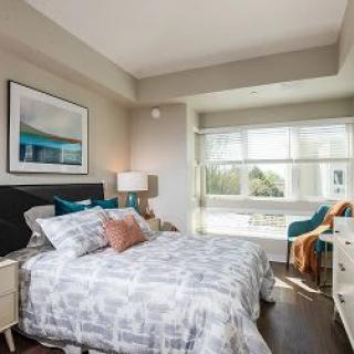 A modern bedroom with a comfortable bed, stylish decor, and large windows allowing natural light.