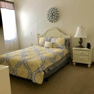 A cozy and well-decorated bedroom with a neatly made bed and a bedside table.