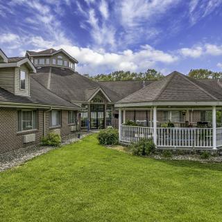 A charming house with a well-maintained lawn and gazebo under a cloudy sky.