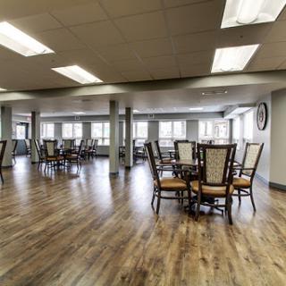 A spacious and well-lit dining area featuring wooden floors and elegant seating.