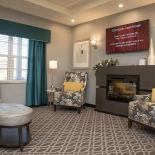 A cozy living room with floral armchairs, a fireplace, and elegant decor.