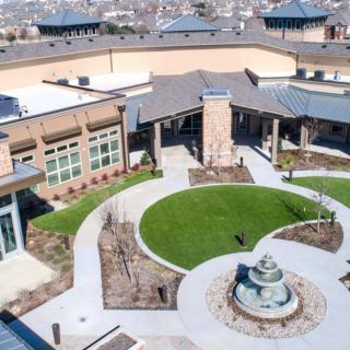 Aerial view of a modern building with a landscaped courtyard featuring a central fountain.
