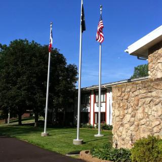 A row of flagpoles with various flags in front of a building under a clear blue sky.