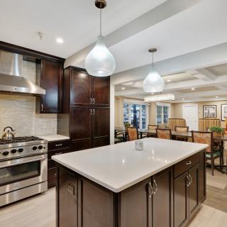 A modern kitchen with a large island, stainless steel appliances, and dark cabinetry.
