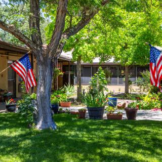 A serene garden with a house in the background, adorned with American flags.