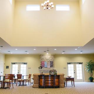 A spacious lobby with a high ceiling, featuring a chandelier and various pieces of furniture.